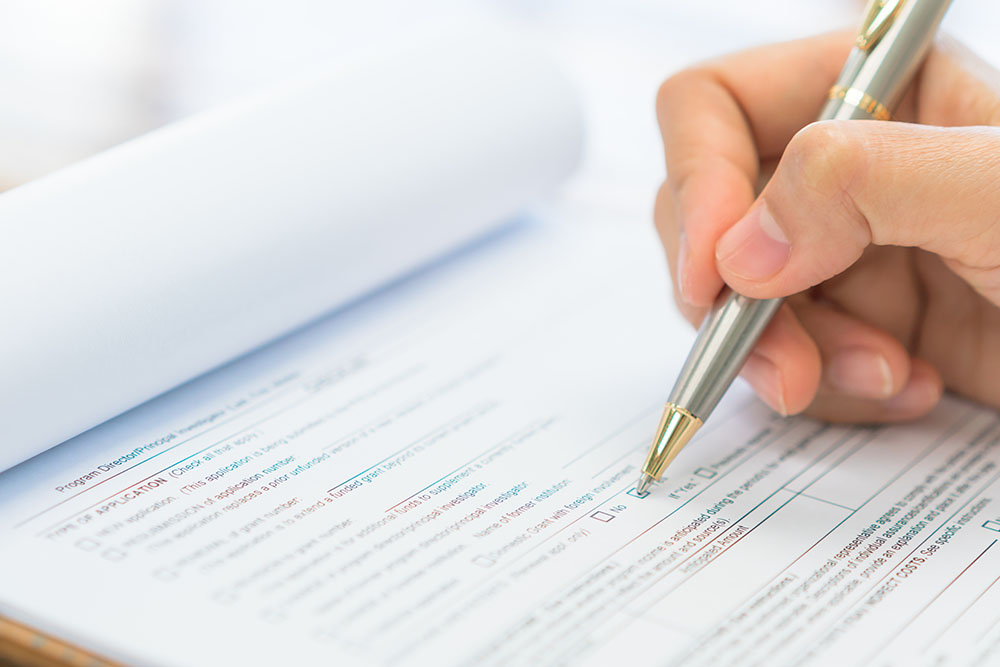 Hand with pen over application form .